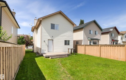 Expansive backyard featuring a green lawn, wood fence, and a raised wooden deck - 9118 Scott Crescent Nw, Edmonton, AB - Outdoor With Exterior