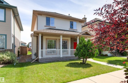 Two-story siding exterior with a covered porch, white railings, and a red entry door - 9118 Scott Crescent Nw, Edmonton, AB - Outdoor With Deck Patio Veranda
