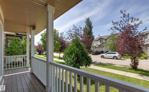 Covered front porch with wood-finish flooring, white railing, and architectural columns - 9118 Scott Crescent Nw, Edmonton, AB - Outdoor With Deck Patio Veranda With Exterior