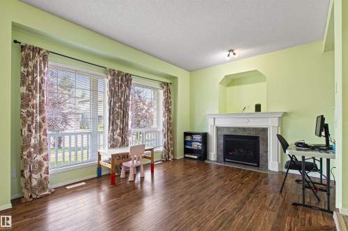 Expansive room featuring wood-finish flooring, large windows, a fireplace with a mantel, and a built-in wall niche - 9118 Scott Crescent Nw, Edmonton, AB - Indoor Photo Showing Living Room With Fireplace