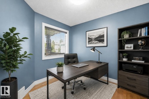 Hardwood-style flooring, a window with horizontal blinds, built-in shelving, and a desk with storage - 49 Navajo Ln, Fort Saskatchewan, AB - Indoor Photo Showing Office