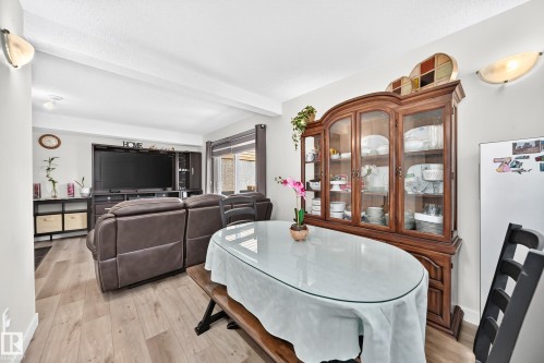Open-concept living area featuring wood-finish flooring, recessed lighting, and wall-mounted sconces - #22 3812 20 Av Nw, Edmonton, AB - Indoor