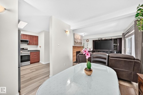 Kitchen with wood-finish flooring, stainless steel appliances, and a skylight - #22 3812 20 Av Nw, Edmonton, AB - Indoor Photo Showing Dining Room