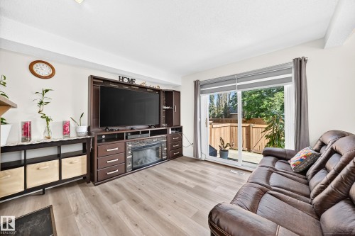 Wood-finish flooring throughout, bright white walls, and a recessed ceiling light - #22 3812 20 Av Nw, Edmonton, AB - Indoor Photo Showing Living Room
