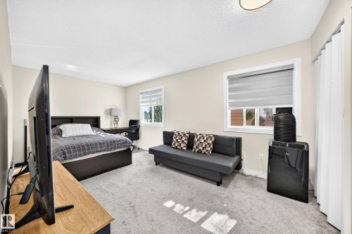 Carpeted flooring, two windows with blinds, a built-in bed frame with shelving, and light-colored walls - #22 3812 20 Av Nw, Edmonton, AB - Indoor Photo Showing Bedroom