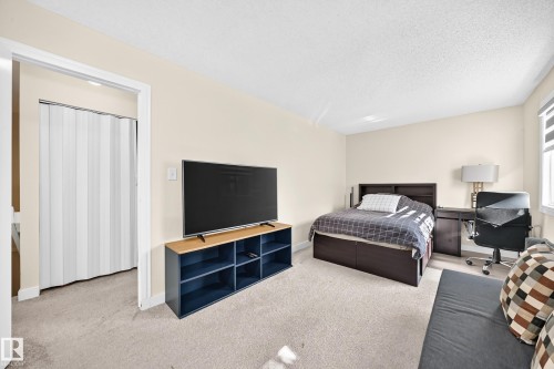 Spacious room with light-toned walls, neutral carpet flooring, and a window with roller shades - #22 3812 20 Av Nw, Edmonton, AB - Indoor Photo Showing Bedroom