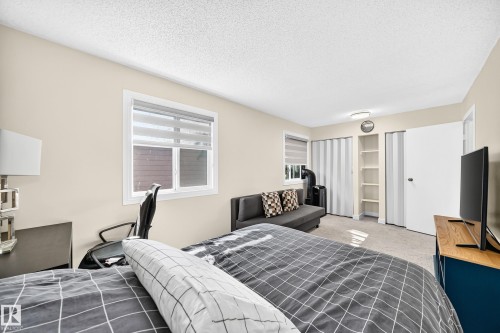 White-framed window with blinds, built-in shelving, white paneled door, and carpeted flooring - #22 3812 20 Av Nw, Edmonton, AB - Indoor Photo Showing Bedroom