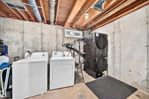 Laundry area with exposed joists, concrete walls, and a drain - #22 3812 20 Av Nw, Edmonton, AB - Indoor Photo Showing Laundry Room