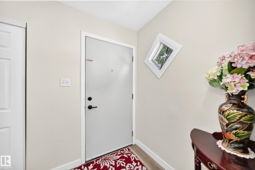 Entryway featuring a white door, light-colored walls, wood-finish flooring, and an angled window - #22 3812 20 Av Nw, Edmonton, AB - Indoor Photo Showing Other Room