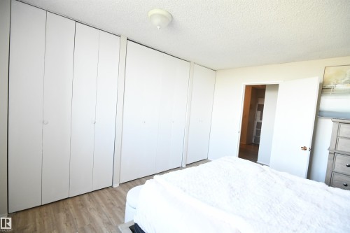 The master bedroom easily supports king sized furniture, has a great window for light and view, as well as a full wall of floor to ceiling closets - #1305 13910 Stony Plain Rd Nw, Edmonton, AB - Indoor Photo Showing Bedroom