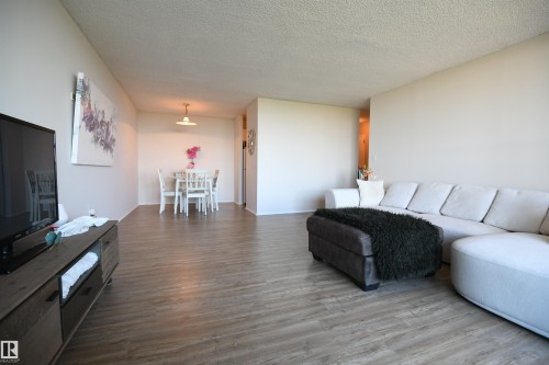 The dining area is open to the living room, with easy access to the white, walk through, galley kitchen - #1305 13910 Stony Plain Rd Nw, Edmonton, AB - Indoor Photo Showing Living Room