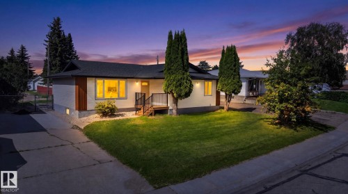 Exterior featuring light-colored siding, shingles, a concrete driveway, and a front lawn with mature trees - 5 Peace River Drive, Devon, AB - Outdoor