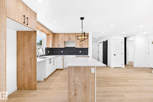 Open-concept kitchen with wood-finish flooring, two-tone cabinetry, a black mosaic tile backsplash, a kitchen island with seating, and recessed lighting - 5 Peace River Drive, Devon, AB - Indoor Photo Showing Kitchen