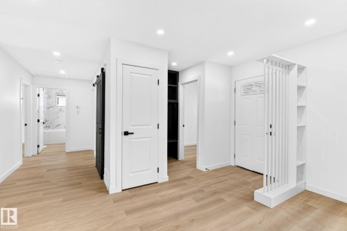Wood-finish flooring throughout, recessed lighting, white walls, built-in shelving, and a sliding barn door - 5 Peace River Drive, Devon, AB - Indoor Photo Showing Other Room