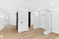 Wood-finish flooring throughout, recessed lighting, white walls, built-in shelving, and a sliding barn door - 