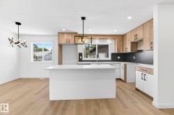 Kitchen featuring a white island with a light-colored countertop, wood-finish cabinetry, white lower cabinetry, black herringbone pattern backsplash, and wood-finish flooring - 