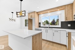 Kitchen featuring wood-finish cabinetry, white countertops, and a black geometric backsplash - 