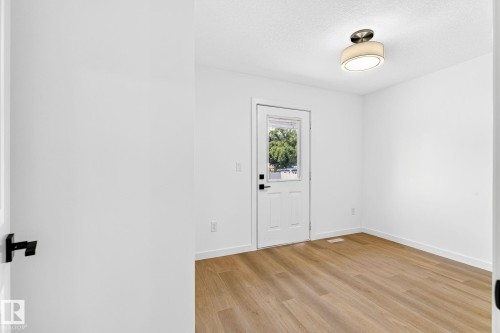 Wood-finish flooring, white walls, white trim, recessed ceiling light fixture, and a glass-paneled exterior door - 5 Peace River Drive, Devon, AB - Indoor Photo Showing Other Room