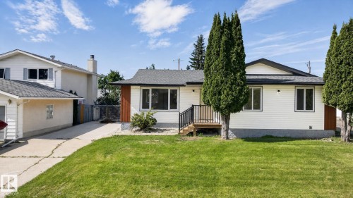 Ranch-style residence featuring white siding, a dark shingle roof, and a front wooden deck with black railings - 5 Peace River Drive, Devon, AB - Outdoor