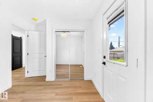 Wood-finish flooring, white panel doors, mirrored closet doors, and a black barn door - 5 Peace River Drive, Devon, AB - Indoor Photo Showing Other Room