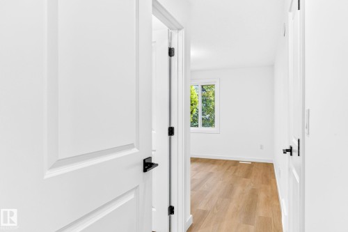 Recessed panel doors with matte black hardware, wood-finish flooring, and a window providing natural illumination - 5 Peace River Drive, Devon, AB - Indoor Photo Showing Other Room
