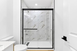 Shower enclosure with black-framed glass, marble-look tile surround, and a white shower pan - 