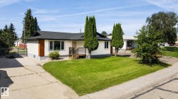 Ranch-style residence featuring a dark shingle roof, light-colored siding, and a contrasting wood-finish accent panel - 