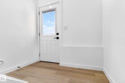 White paneled door with a half-lite window and matte black hardware - 