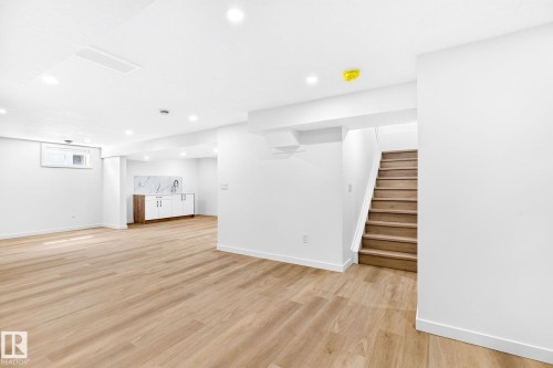 Spacious open-concept room featuring wood-finish flooring, recessed lighting, and a built-in wet bar with white cabinetry and a patterned backsplash - 5 Peace River Drive, Devon, AB - Indoor Photo Showing Other Room