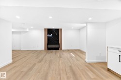 Spacious open-concept room featuring wood-finish flooring, recessed lighting, and a contemporary linear fireplace - 