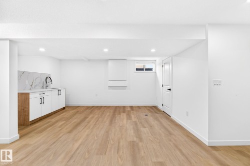 Recessed lighting, wood-finish flooring, built-in cabinetry with a sink, white quartz-look countertop, and a white interior door - 5 Peace River Drive, Devon, AB - Indoor
