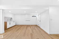 Recessed lighting, wood-finish flooring, built-in cabinetry with a sink, white quartz-look countertop, and a white interior door - 