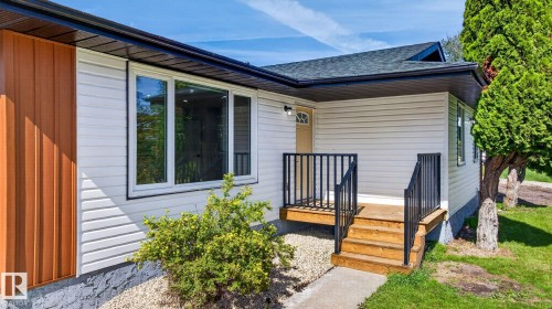 White vinyl siding exterior with an accent wood-finish panel - 5 Peace River Drive, Devon, AB - Outdoor With Exterior