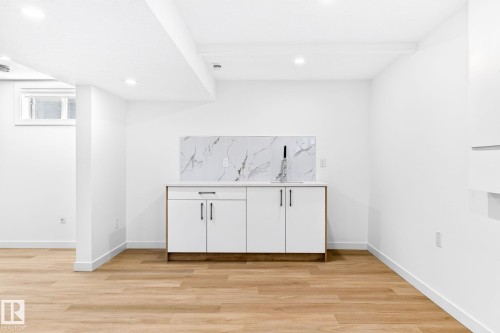 Wet bar with white cabinetry, a light-toned countertop, and a marble-patterned backsplash - 5 Peace River Drive, Devon, AB - Indoor Photo Showing Other Room