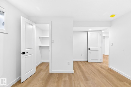 Wood-finish flooring, white walls, built-in closet shelving, recessed lighting, and white paneled doors with matte black hardware - 5 Peace River Drive, Devon, AB - Indoor Photo Showing Other Room