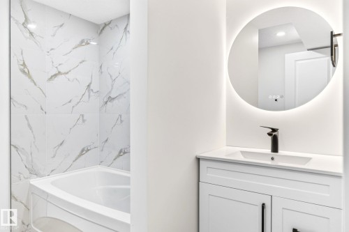 White vanity with a rectangular undermount sink, a matte black faucet, and an illuminated circular mirror - 5 Peace River Drive, Devon, AB - Indoor Photo Showing Bathroom
