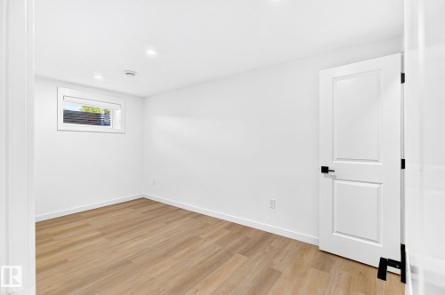 Recessed lighting, wood-finish flooring, white walls, white trim, and a white paneled door with matte black hardware - 5 Peace River Drive, Devon, AB - Indoor Photo Showing Other Room