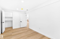 Recessed lighting, wood-finish flooring, white walls, built-in shelving, and contemporary black hardware - 