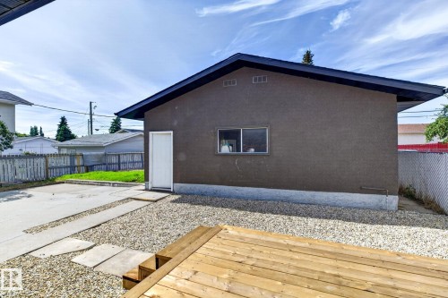 Detached structure with a stucco exterior, a wood deck, gravel landscaping, and a concrete pathway - 5 Peace River Drive, Devon, AB - Outdoor With Exterior