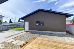 Detached structure with a stucco exterior, a wood deck, gravel landscaping, and a concrete pathway - 