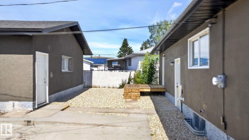 Private yard area featuring a raised wood deck, gravel landscaping, white fencing, and concrete pathways - 5 Peace River Drive, Devon, AB - Outdoor With Exterior