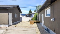 Private yard area featuring a raised wood deck, gravel landscaping, white fencing, and concrete pathways - 
