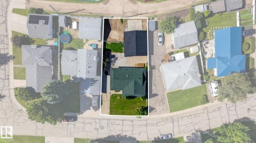 Property featuring a main residence with a green shingle roof, a detached structure with a dark shingle roof, a paved driveway, and a grassed yard - 5 Peace River Drive, Devon, AB - 