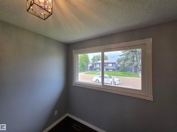 Bright corner bedroom featuring expansive picture window with natural light, neutral paint finish, and textured ceiling detail - 
