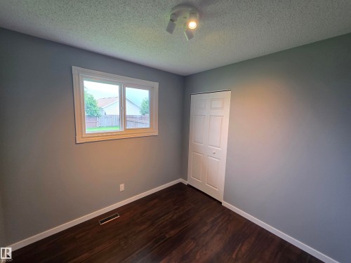 Room featuring gray walls, dark wood-finish flooring, and a white bi-fold closet door - 1907 145A Avenue Nw, Edmonton, AB - Indoor Photo Showing Other Room