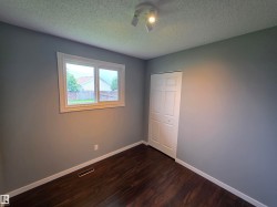 Room featuring gray walls, dark wood-finish flooring, and a white bi-fold closet door - 