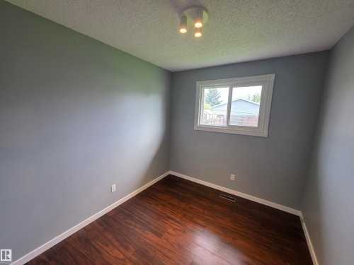Wood-finish flooring, neutral gray walls, bright white trim, and a ceiling-mounted light fixture - 1907 145A Avenue Nw, Edmonton, AB - Indoor Photo Showing Other Room