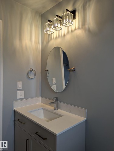 Vanity featuring a rectangular undermount sink, a chrome single-handle faucet, and white countertop with matching backsplash - 1907 145A Avenue Nw, Edmonton, AB - Indoor Photo Showing Bathroom
