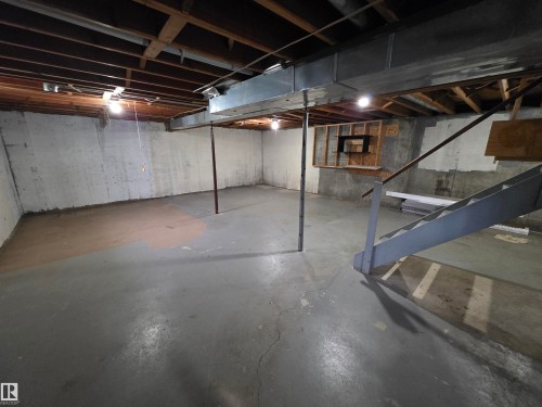 Expansive unfinished basement featuring concrete walls and flooring, exposed ceiling joists, and a metal staircase with railing - 1907 145A Avenue Nw, Edmonton, AB - Indoor Photo Showing Basement