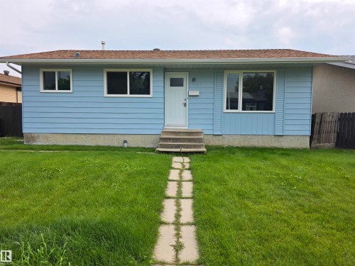 Light blue horizontal siding, white trim windows, white entry door, concrete steps, and a concrete paver walkway - 1907 145A Avenue Nw, Edmonton, AB - Outdoor